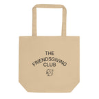 A beige canvas tote bag with black printed text reading 'THE FRIENDSGIVING CLUB' and a small squirrel illustration on the front, shown against a plain white background.