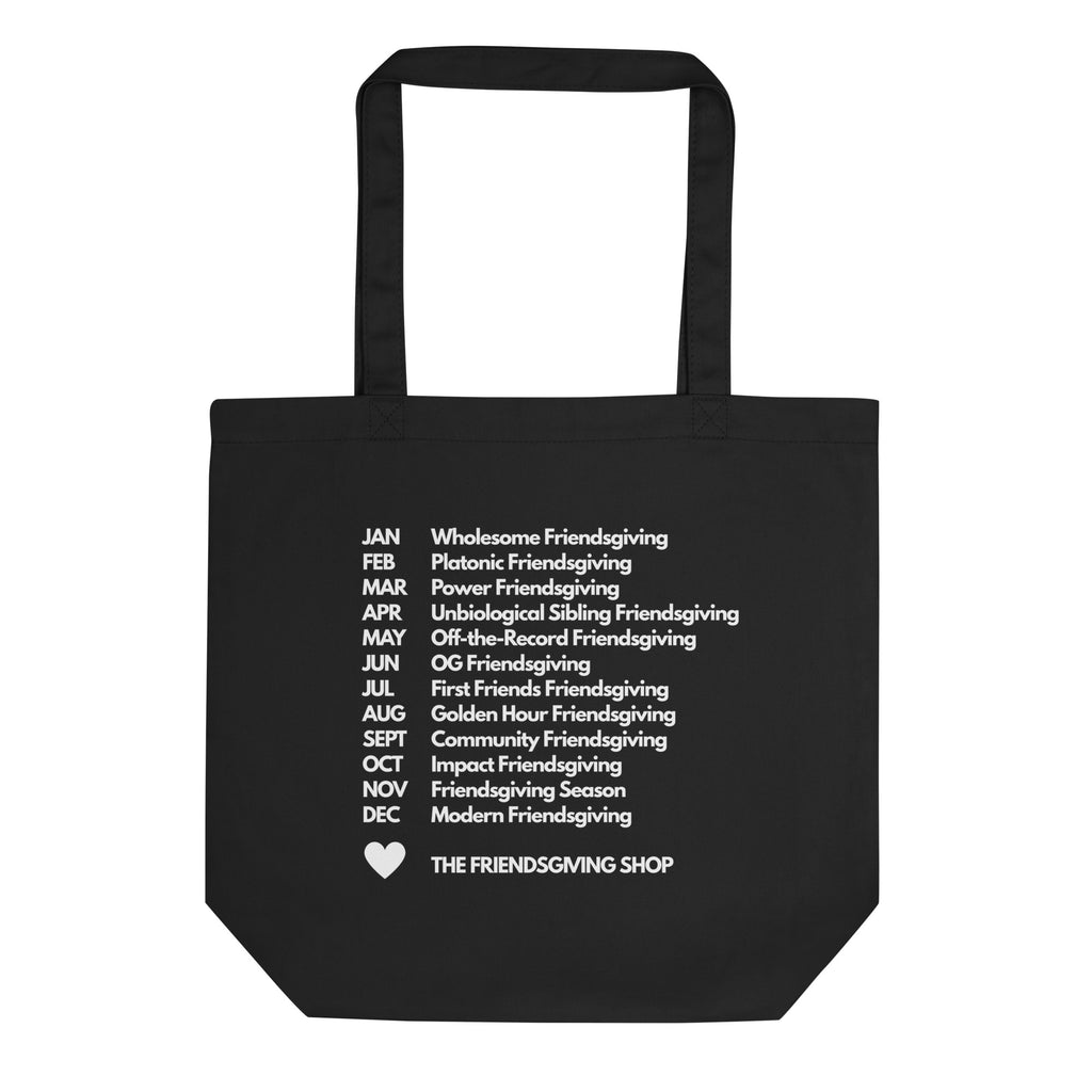 A black canvas tote bag with white printed text listing various types of friends giving throughout the year, ending with 'THE FRIENDSGIVING SHOP' and a small heart icon. The bag is shown against a plain white background.