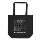 A black canvas tote bag with two handles, featuring a white printed list of 'Noot' days around the calendar and the text 'THE FRIENDSGIVING SHOP' with a small heart at the bottom.