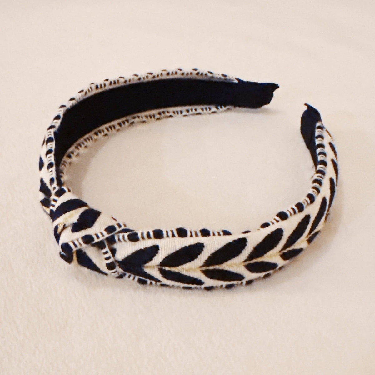 Navy and white patterned headband on a beige background