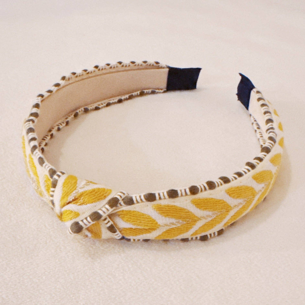 Headband with yellow and white pattern on a beige background