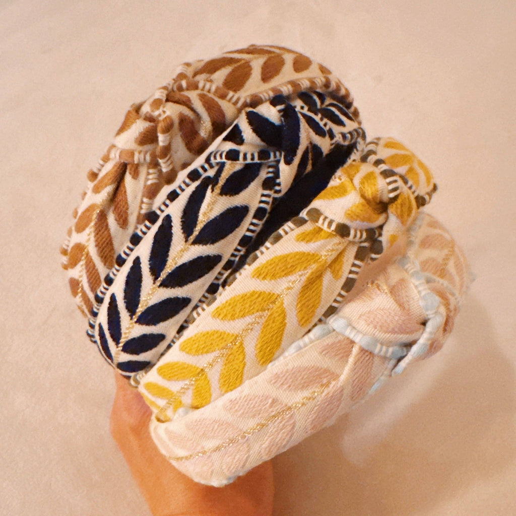 Three patterned headbands stacked on a beige background