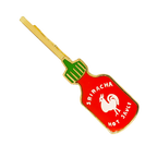 A Sriracha hot sauce bottle-shaped hair clip with red, green, white, and gold enamel details, shown on a plain white background.