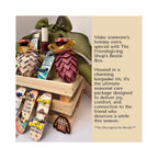 A gift box arrangement labeled 'The Friendsgiving Shop's Bestie Box' shown beside descriptive text. The box contains a large green fabric bag with a bow, jars, decorative pinecones, a small plaid hat, and miniature skateboards in a wooden crate.