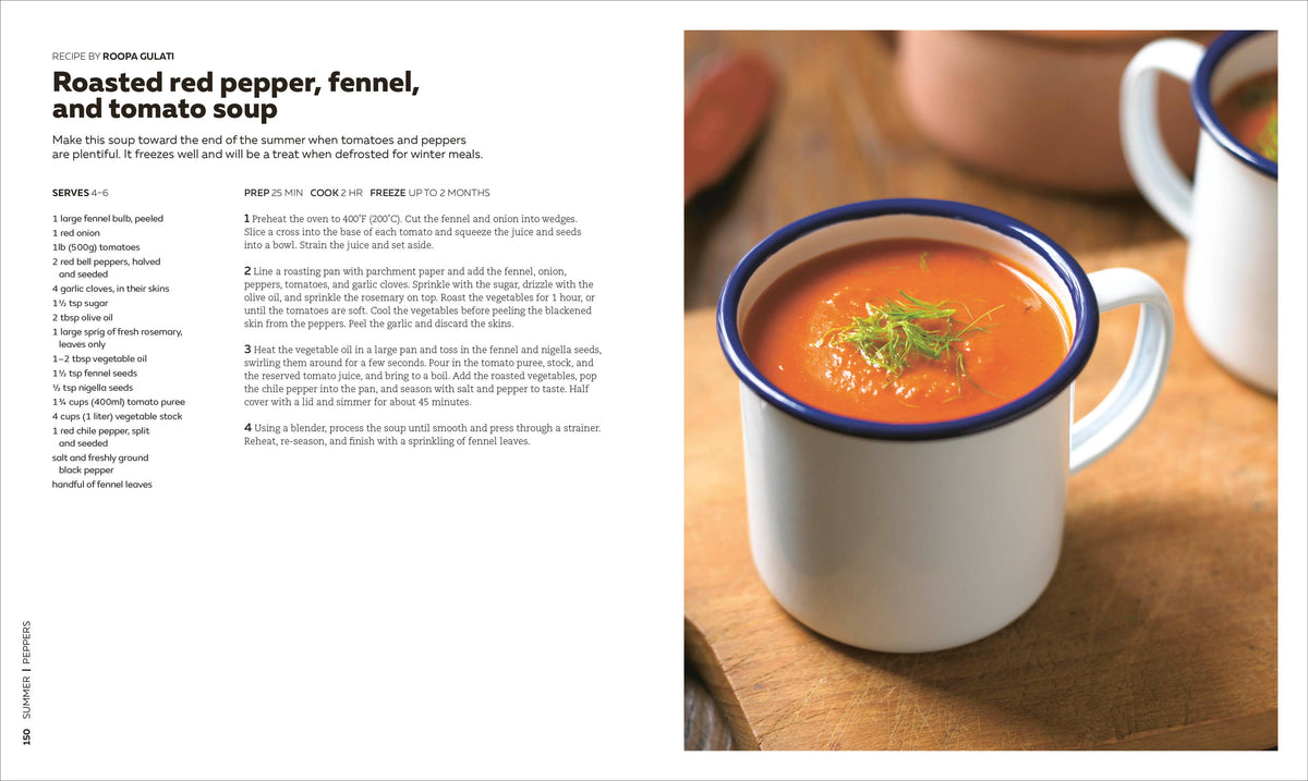 White mug with blue rim filled with roasted red pepper, fennel, and tomato soup on a wooden surface.