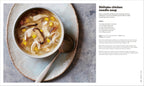 Bowl of Shiitake chicken noodle soup on a textured surface with a spoon