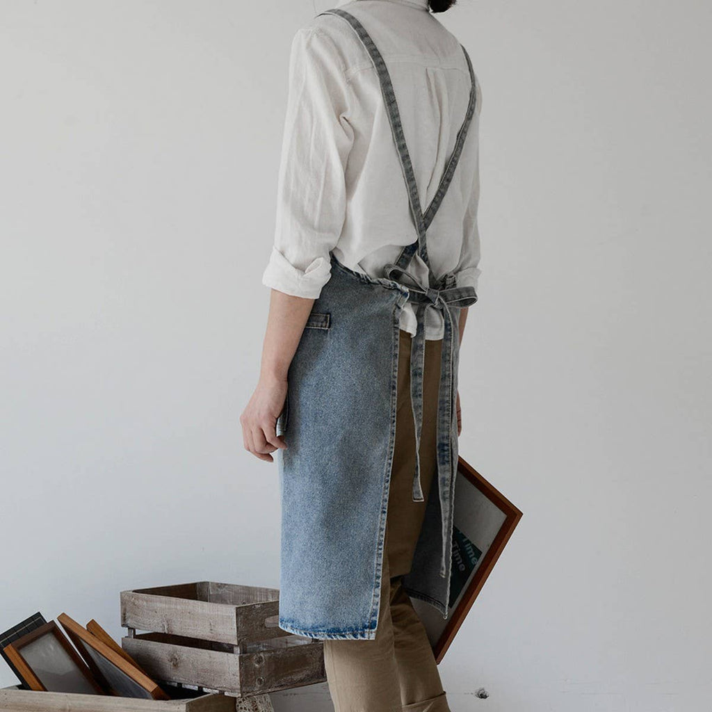 Person wearing a denim apron in a minimalistic setting