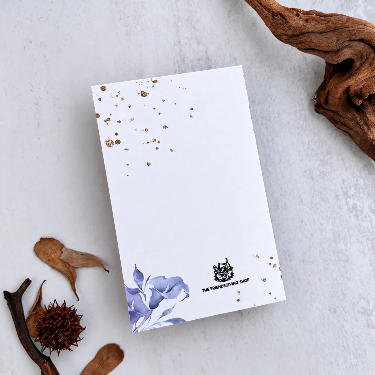 White card with gold specsw and blue floral at bottom