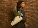 Woman holding a tote bag with flowers against a brick wall